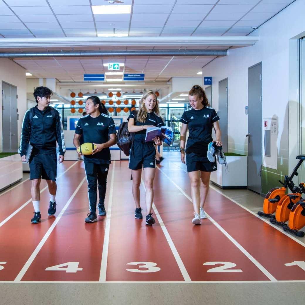 sportkunde en alo samen liggende foto studenten lopen over atletiekbaan binnen bij gymnasion veraf esteban selena carlijn randy 2022