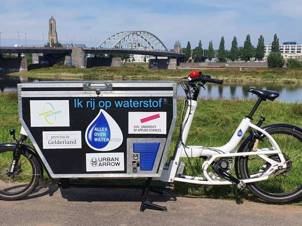 Waterstofbakfiets met natuur, rivier en John Frostbrug Arnhem op de achtergrond