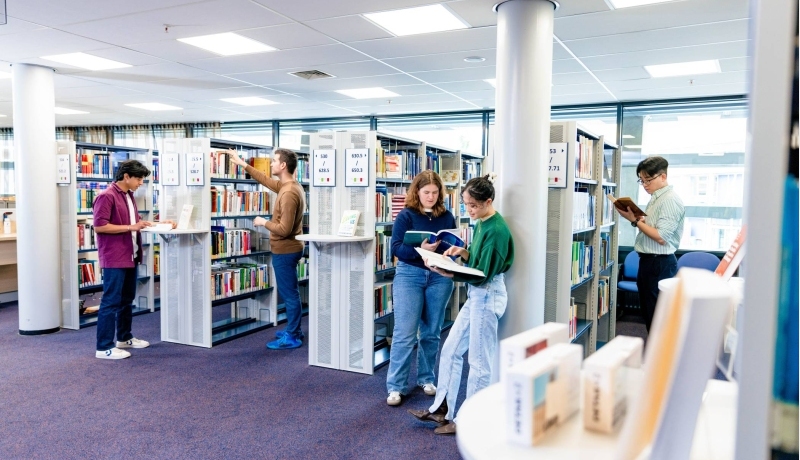International students browsing through study books in the library on the Arnhem campus of HAN University of Applied Sciences.