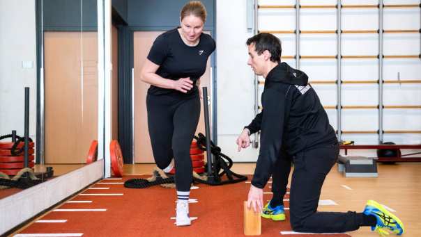 Student rent in de sportzaal, docent controleert de houding.