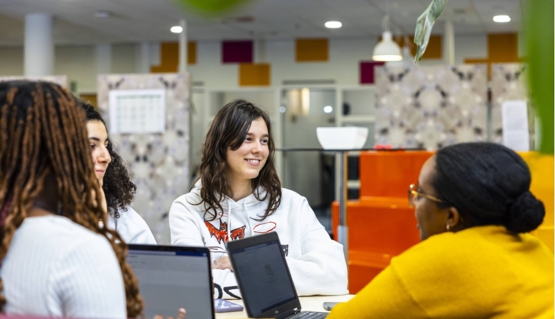 International Social Work. Groepje studenten lachend in een loungebank met laptops op tafel