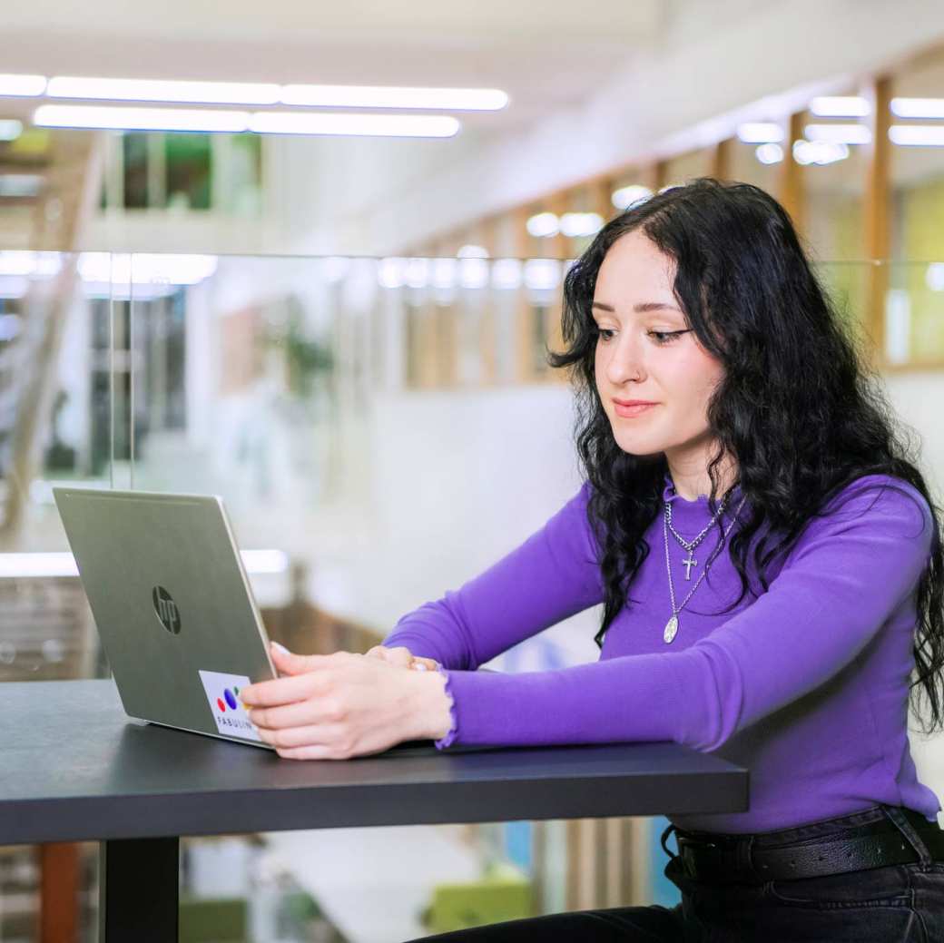 Een student werkt achter haar laptop.
