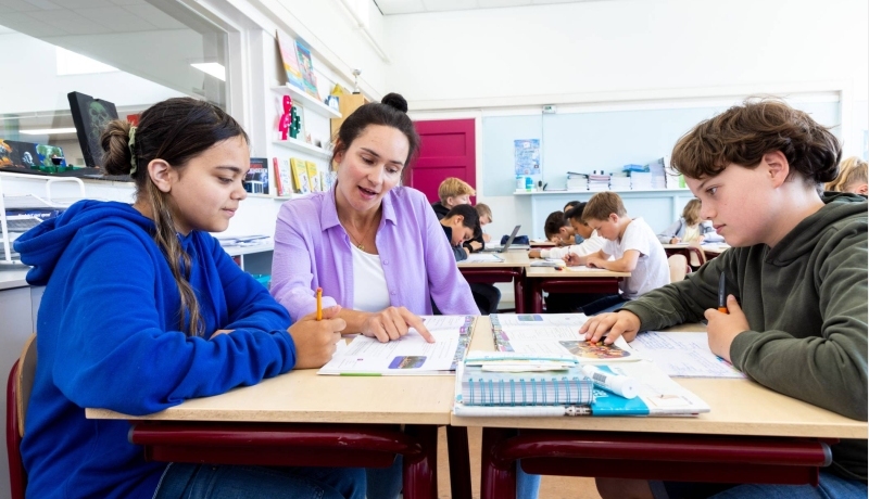 Docent Leonie van de opleiding leraar basisonderwijs aan tafel met leerlingen