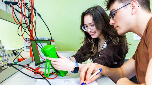 Twee studenten elektrotechniek voeren een experiment uit met een multimeter.