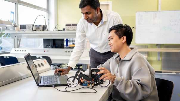 Een docent van de Master Engineering Systems Cyber Physical Systems kijkt mee op de pc van een student.