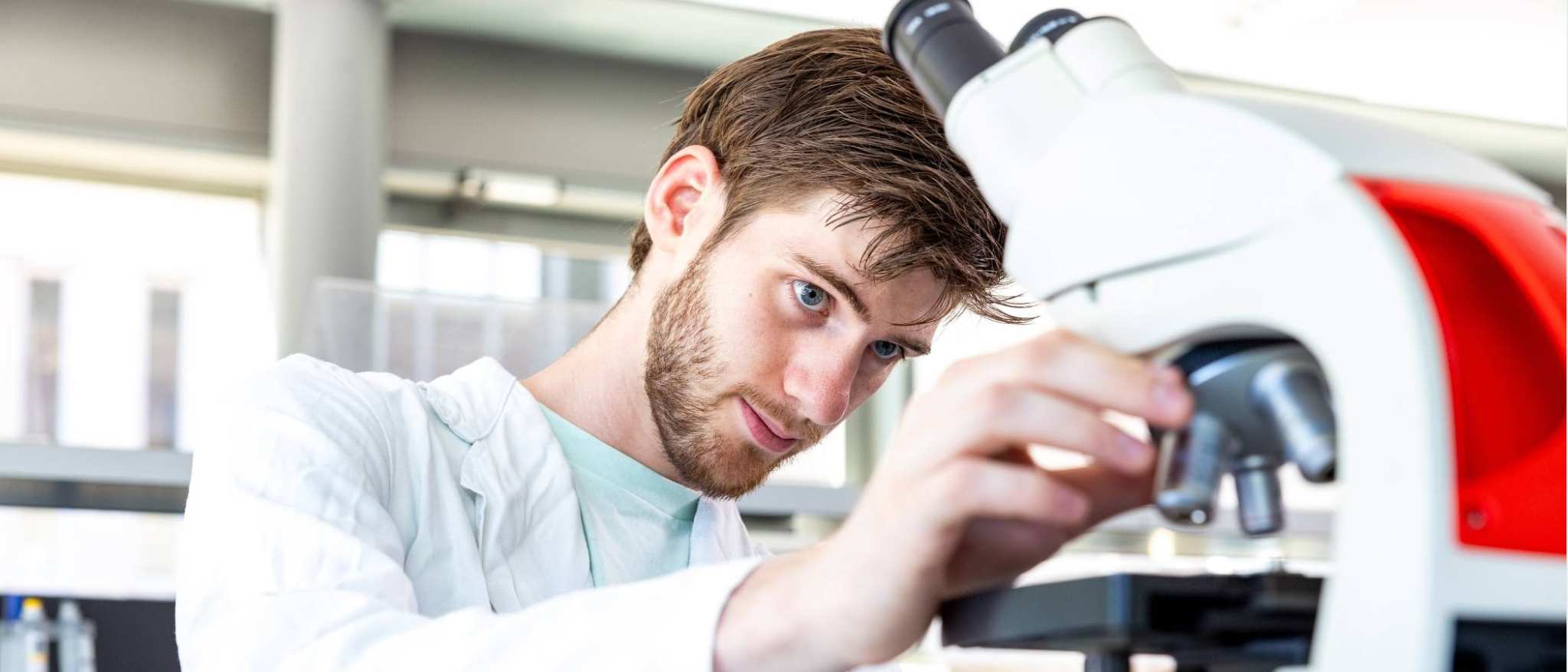 student aan het werk met de microscoop in het lab