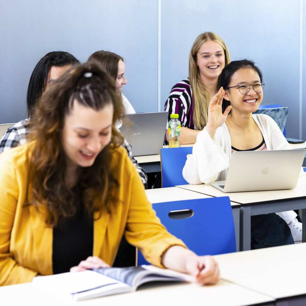 Students in a class, one student puts her hand up