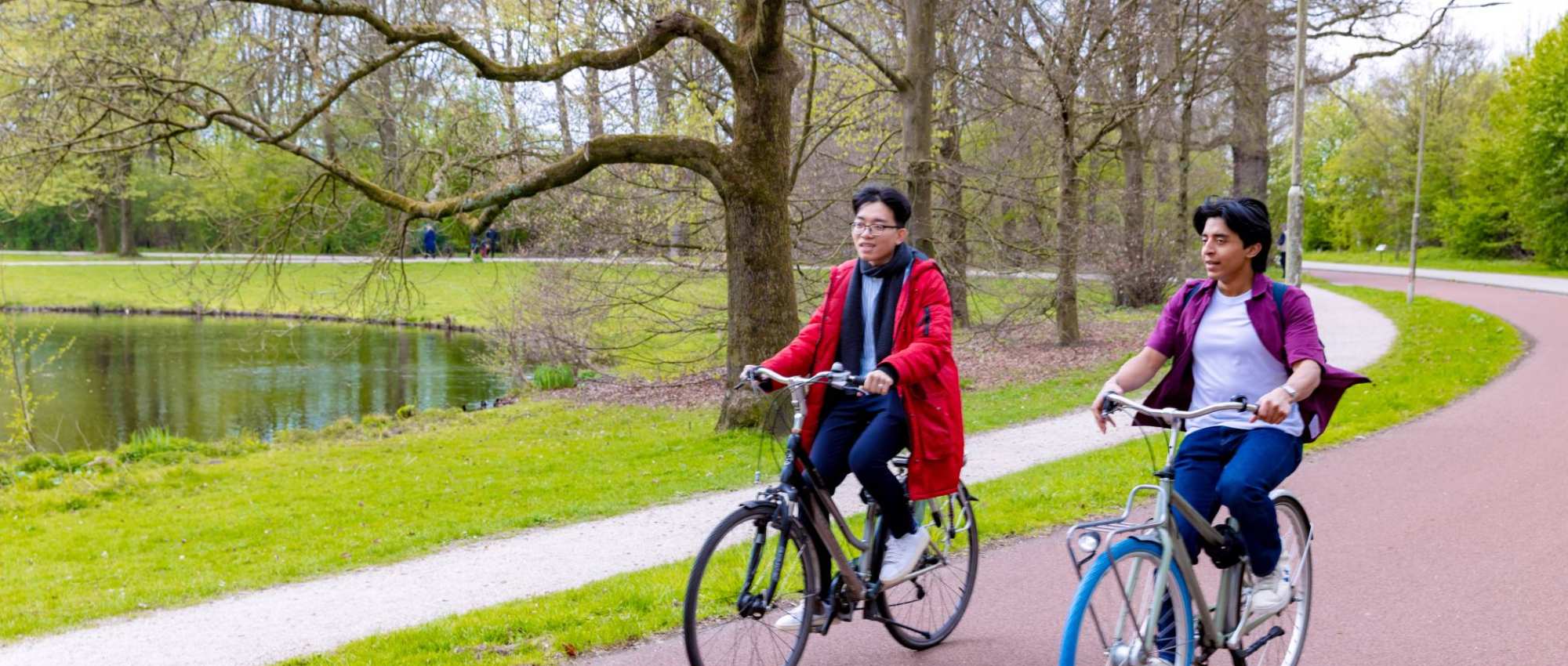 Diego and Nyugen riding their bikes on the bicycle road in the park.