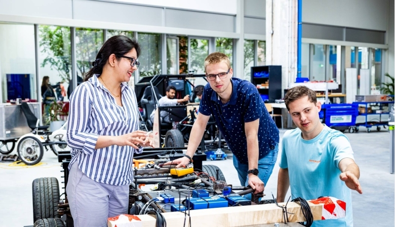 De docent van de Master of Engineering Systems Automotive Systems met twee studenten bij de MORE Vehicle.