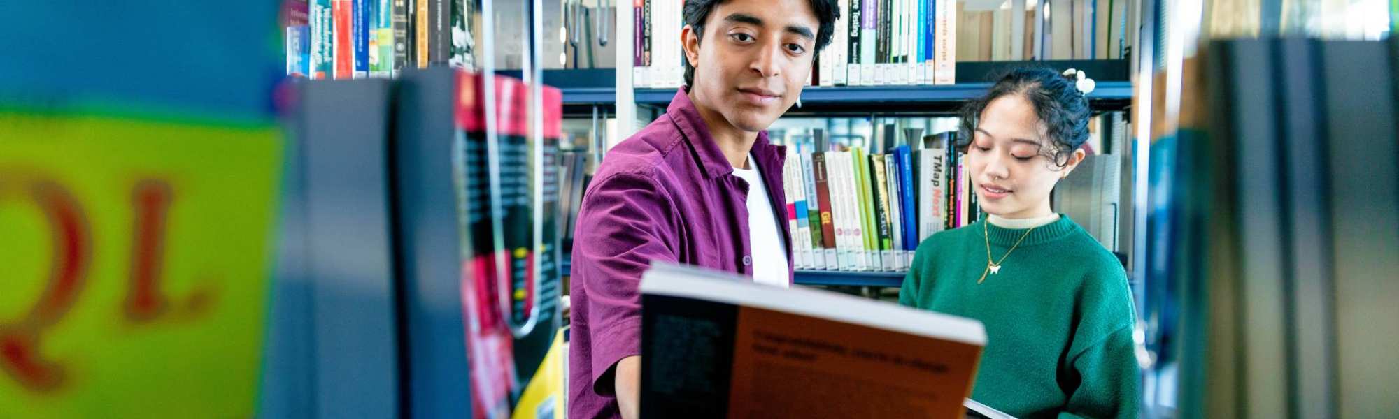 International students Diego and Tam looking for books in the library on the Arnhem campus of HAN University of Applied Sciences.