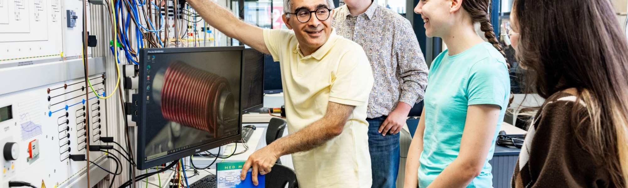 Een docent elektrotechniek geeft uitleg aan studenten in het hoogspanningslab.