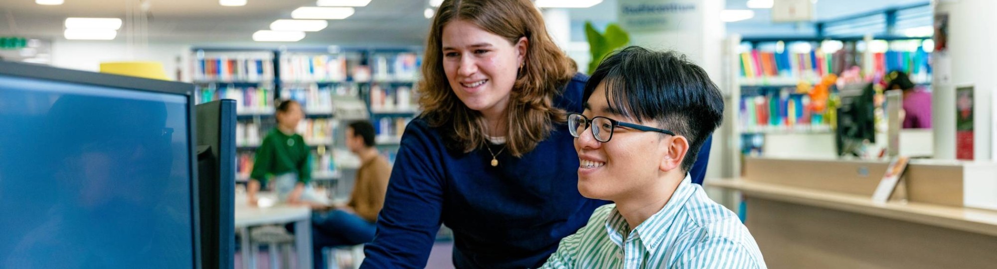 International students Noa and Nyugen looking up information in the library at the Arnhem campus of HAN University of Applied Sciences.