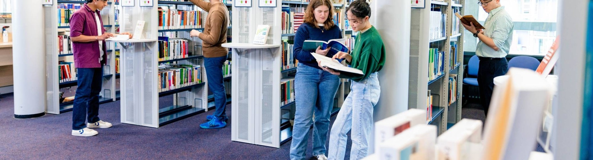 International students browsing through study books in the library on the Arnhem campus of HAN University of Applied Sciences.