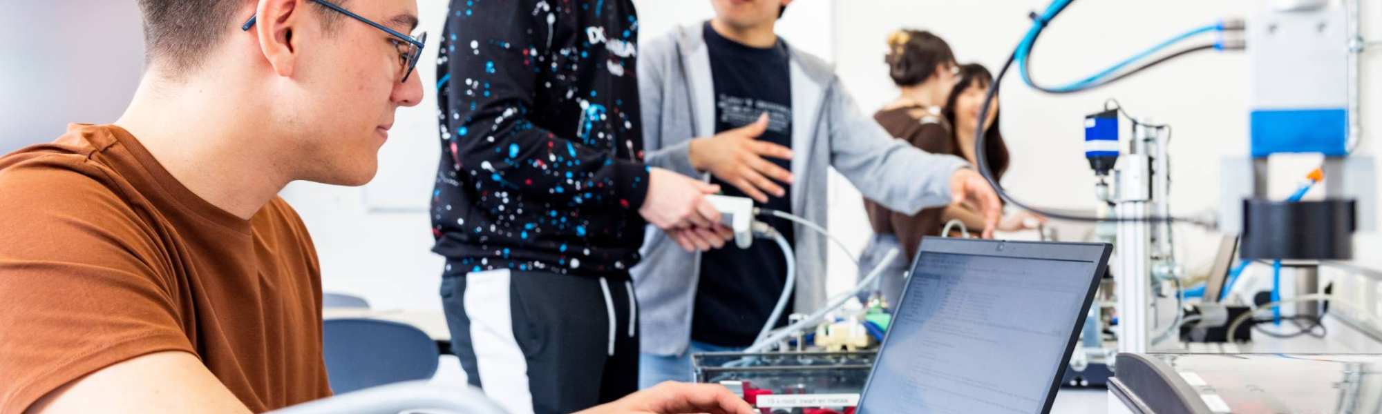 Een elektrotechniekstudent werkt op de laptop tijdens practicum.