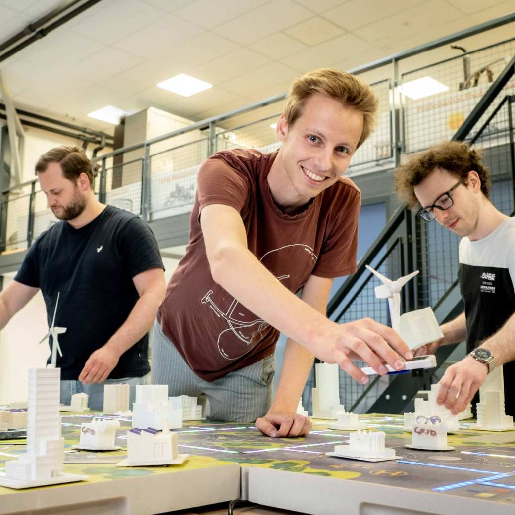 Drie studenten van de masteropleiding Engineering Systems: Sustainable Energy bij de Smart Grid-demotafel.