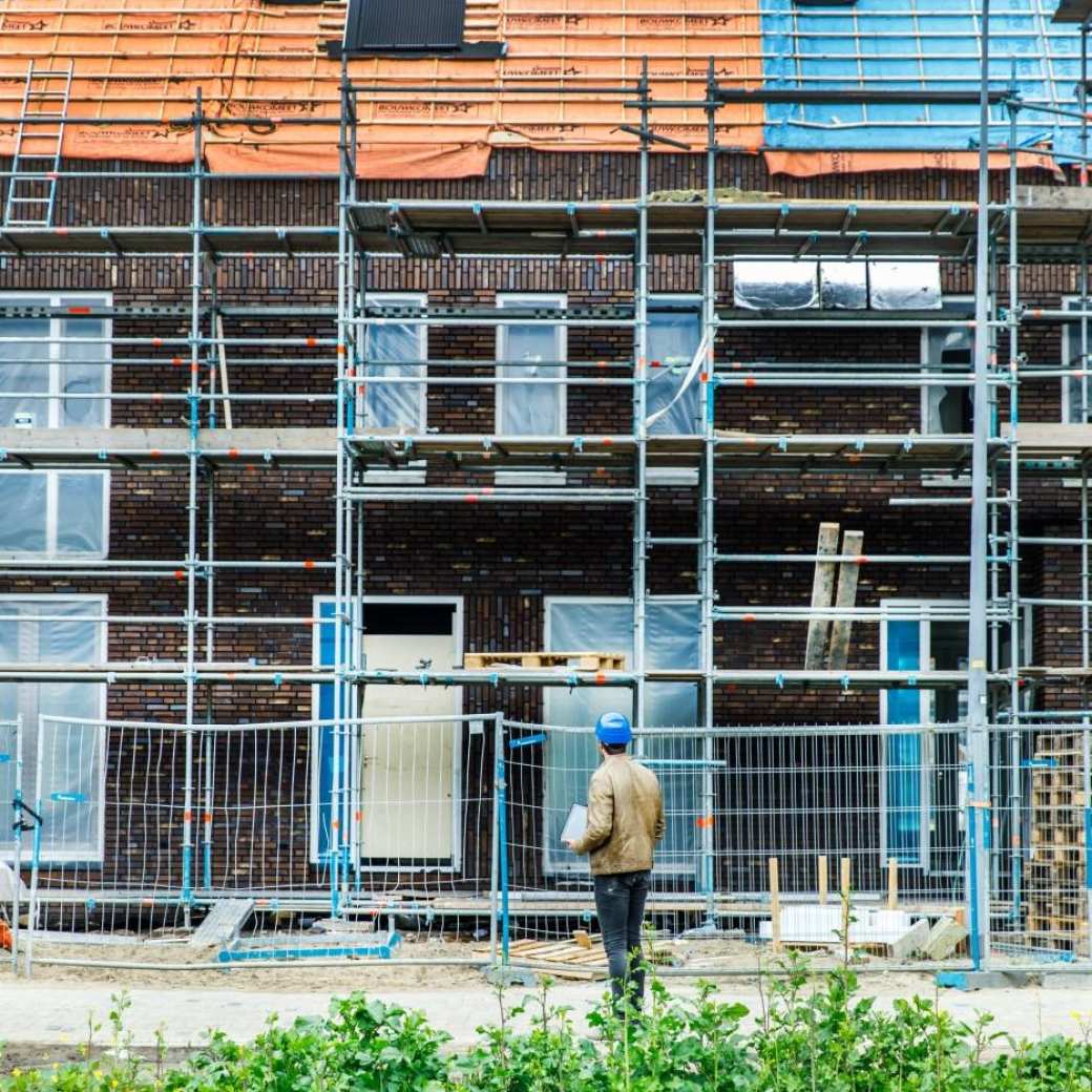 man met blauwe helm bekijkt een bouwproject