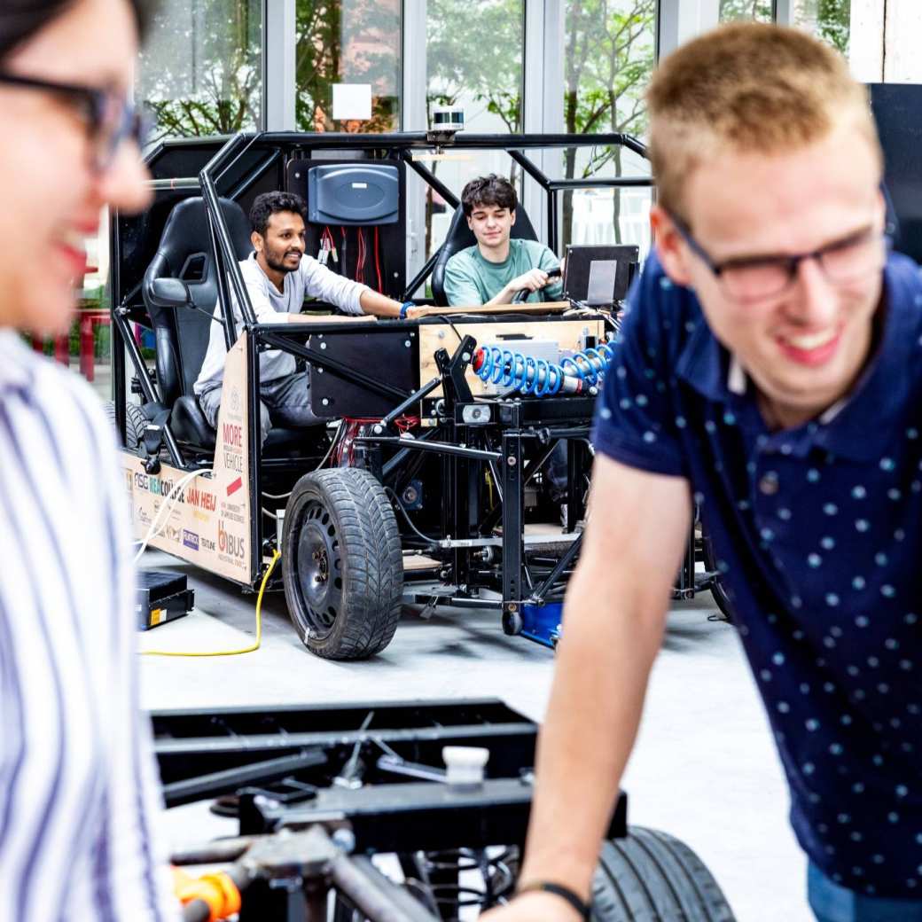 Studenten en docent van de master Engineering Systems Automotive Systems met de MORE Vehicle op de achtergrond.