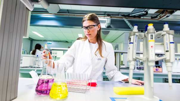 Student in het lab met reageerbuisjes en een pipet