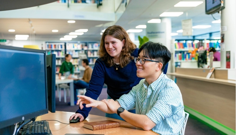 International students Noa and Nyugen looking up information in the library at the Arnhem campus of HAN University of Applied Sciences.