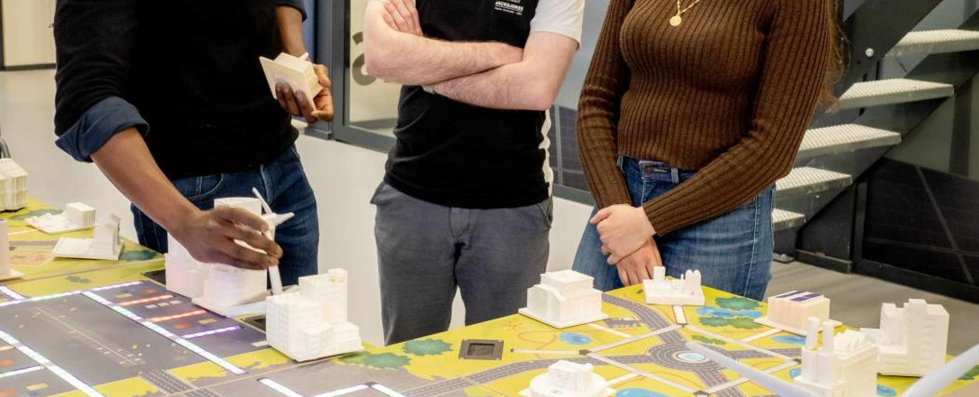 Twee studenten van de Master Engineering Systems Sustainable Energy en een docent bij de Smart Grid-demotafel.