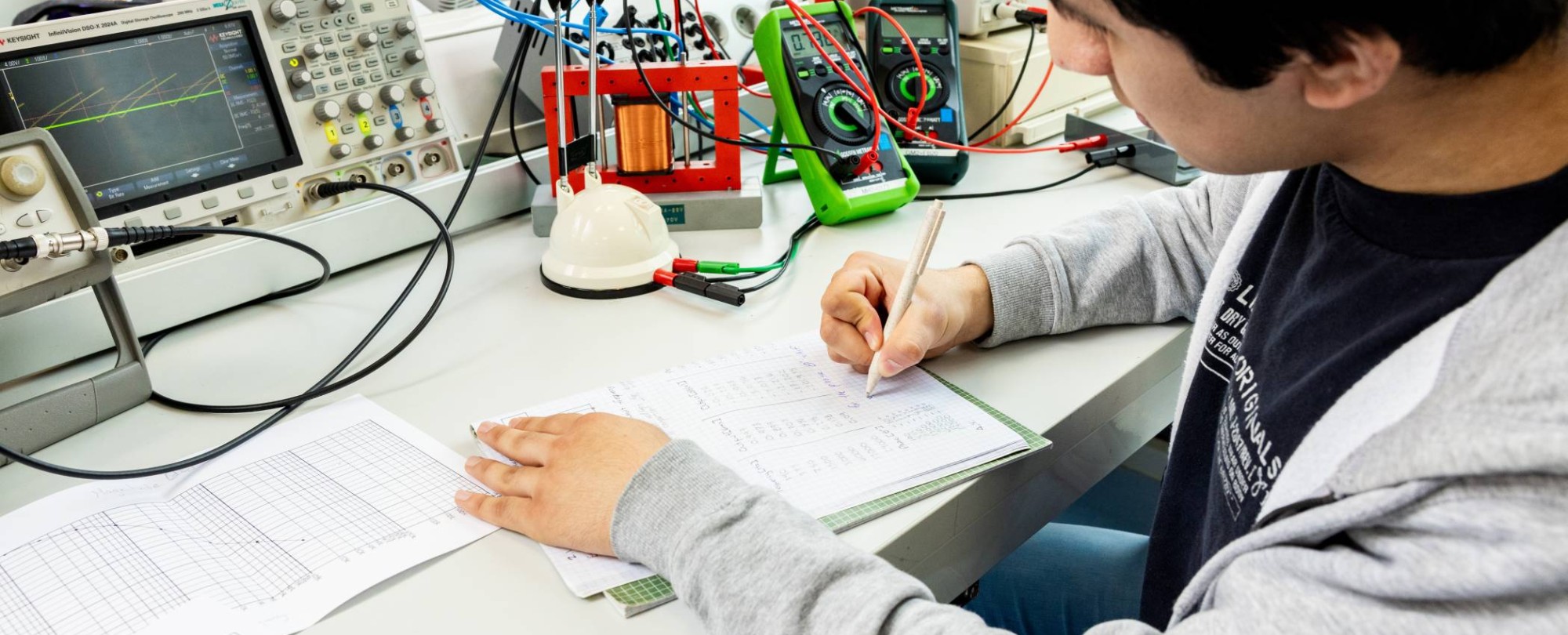 Een student elektrotechniek werkt aan een logboek tijdens het netwerkpracticum.