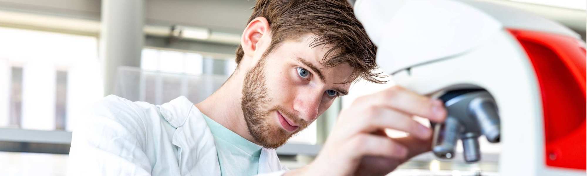 student aan het werk met de microscoop in het lab