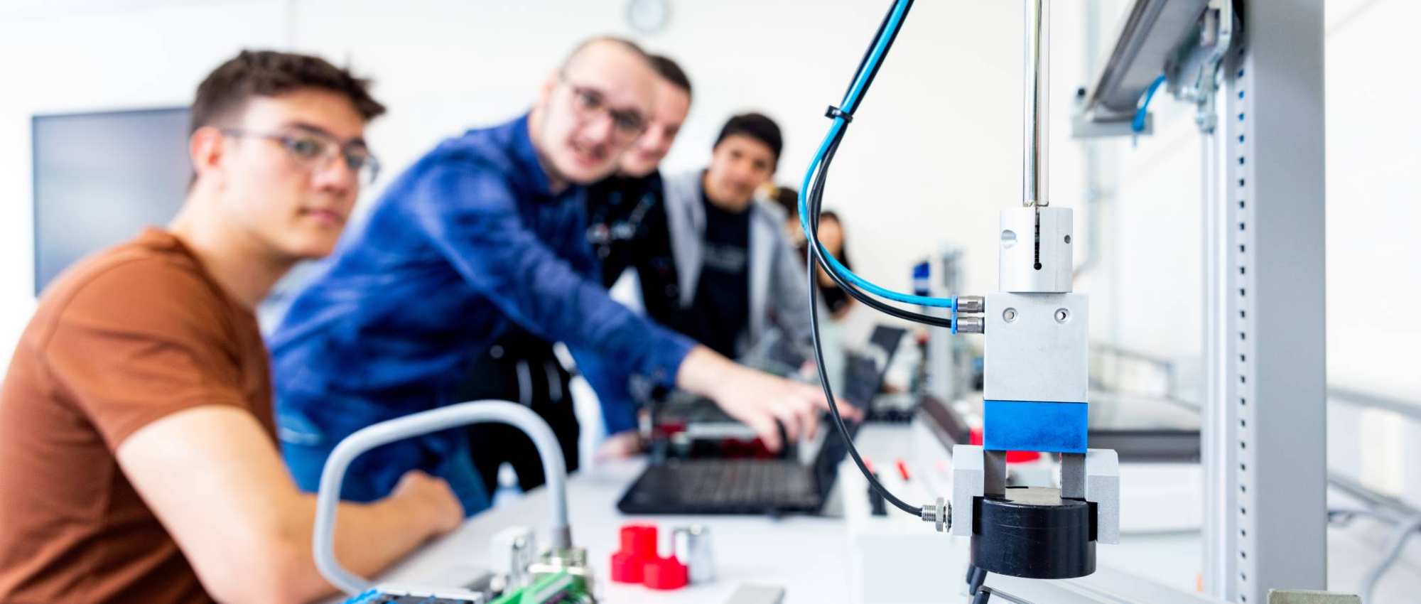 Studenten elektrotechniek werken in een practicumruimte aan een Programmable Logic Controller (PLC).