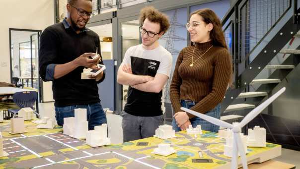 Studenten van de Master Engineering Systems Sustainable Energy en een docent bij de Smart Grid-tafel