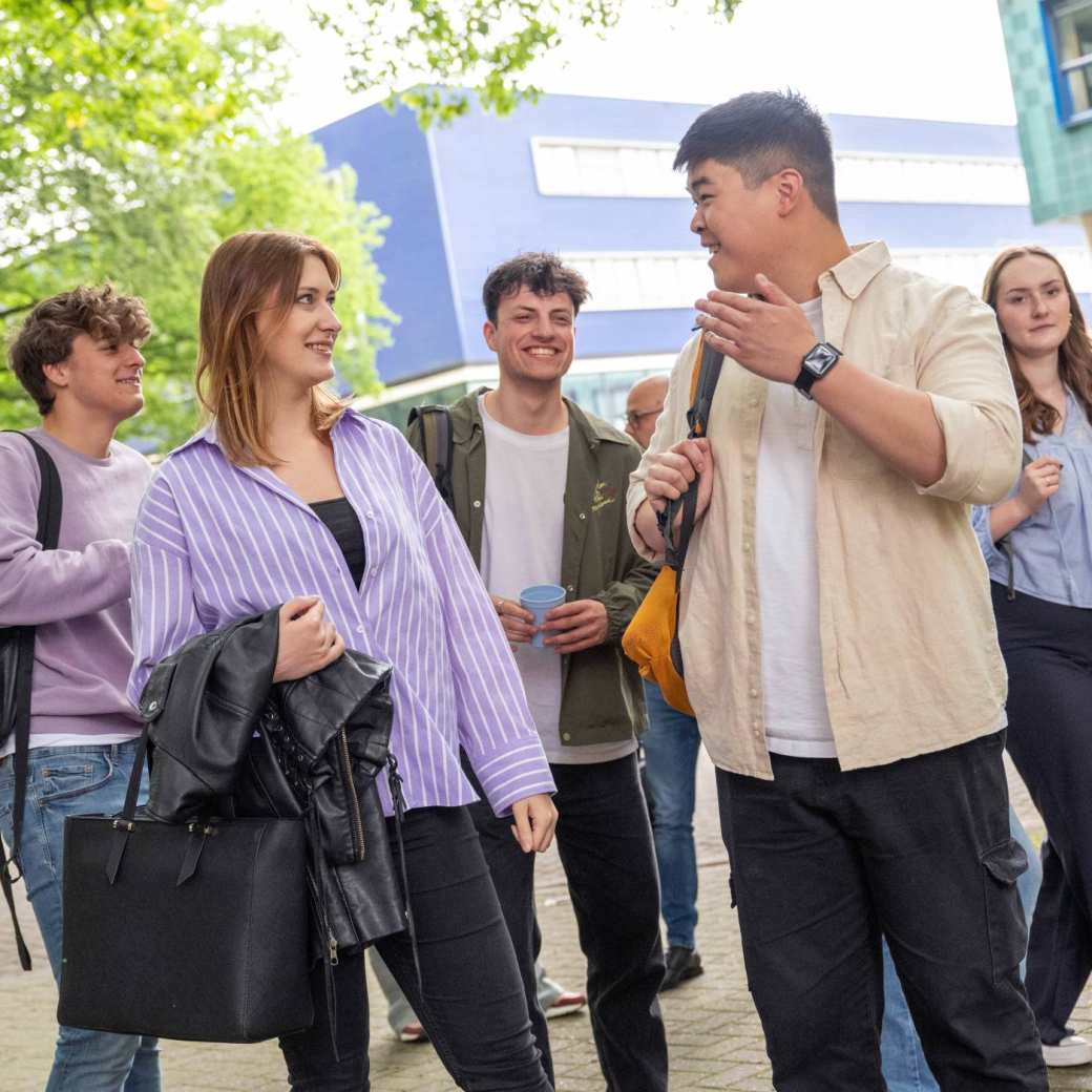 5 studenten lopen buiten en kletsen en lachen