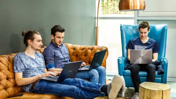 Drie jongens werken op laptop in huiskamer zitje