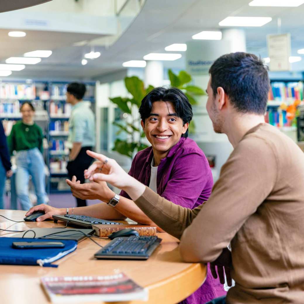 International students Diego and Andrei looking for information in the library at the Arnhem campus of HAN University of Applied Sciences.
