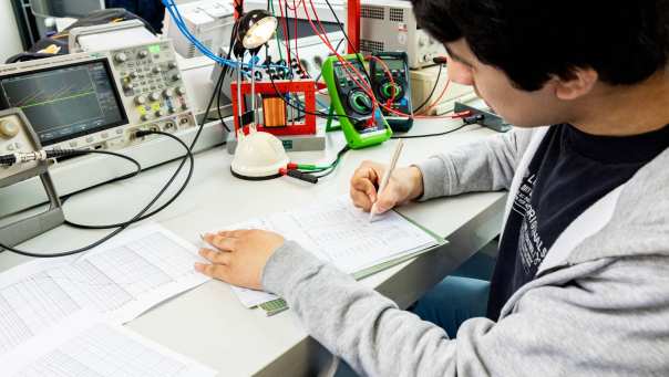 Een student elektrotechniek werkt aan een logboek tijdens het netwerkpracticum.