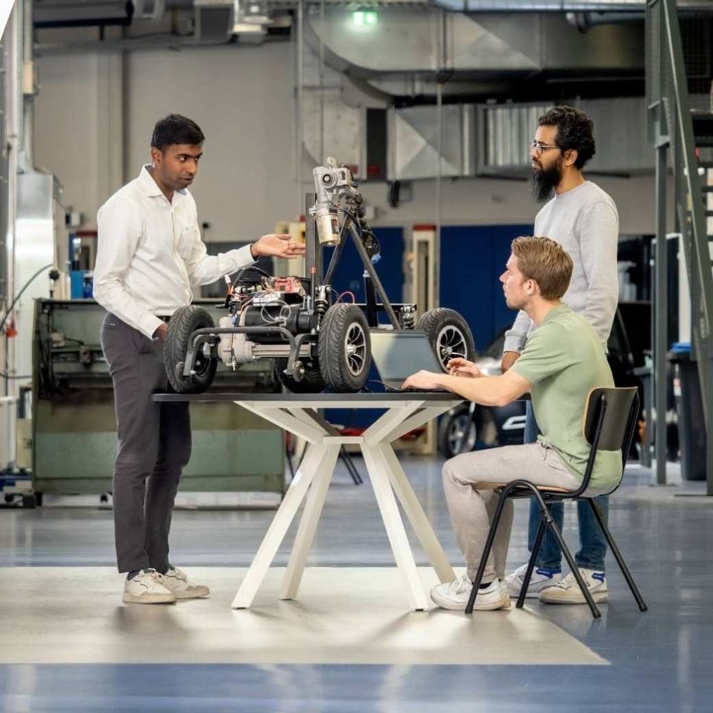 Een docent van de Master Engineering Systems Cyber Physical Systems staat met twee studenten bij het MORE-project, de scootmobiel.