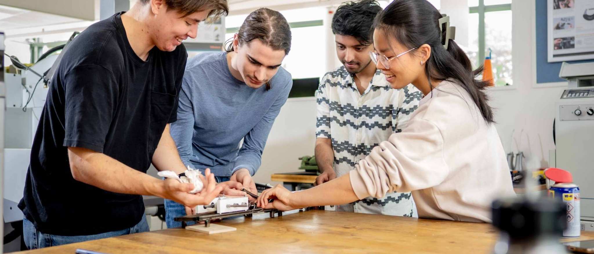 Studenten werktuigbouwkunde moeten samenwerken bij het op spanning brengen van een veer.