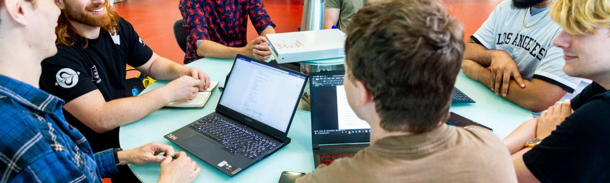 a group of engineering students -mechanical werktuigbouwkunde - working on a project together at a round table with laptops 