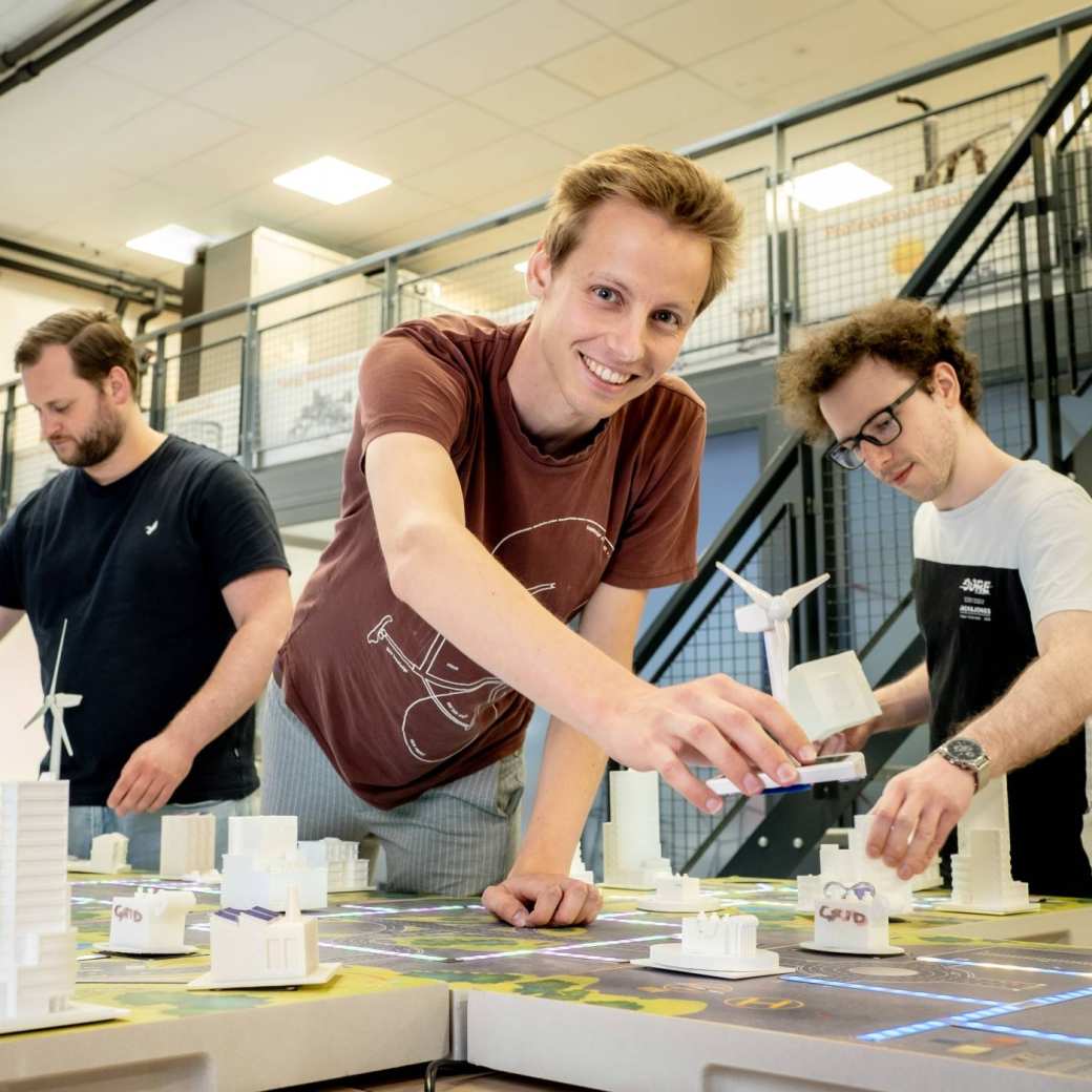 Drie studenten van de masteropleiding Engineering Systems: Sustainable Energy bij de Smart Grid-demotafel.